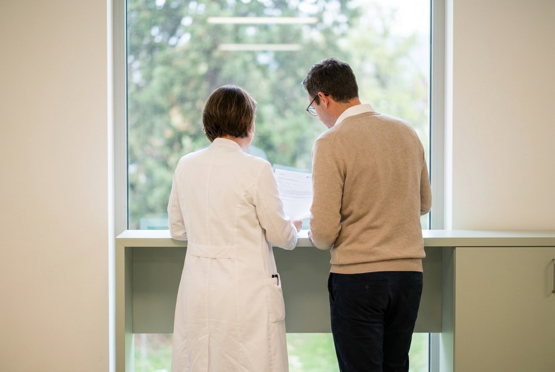 Zwei Fachpersonen im Gespräch am Fenster, von hinten (Demo-Bild)